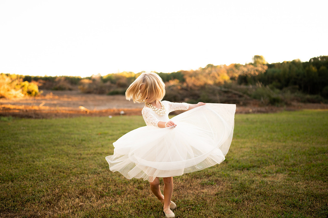 Child twirling in a white dress at sunset