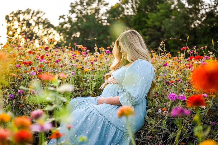 Expecting mother standing among colorful flowers