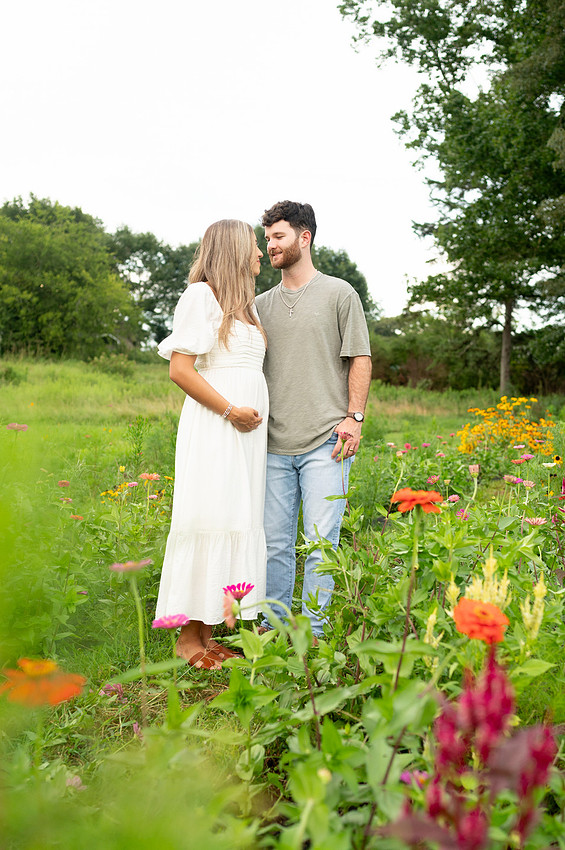 Expecting couple standing together in a wildflower field