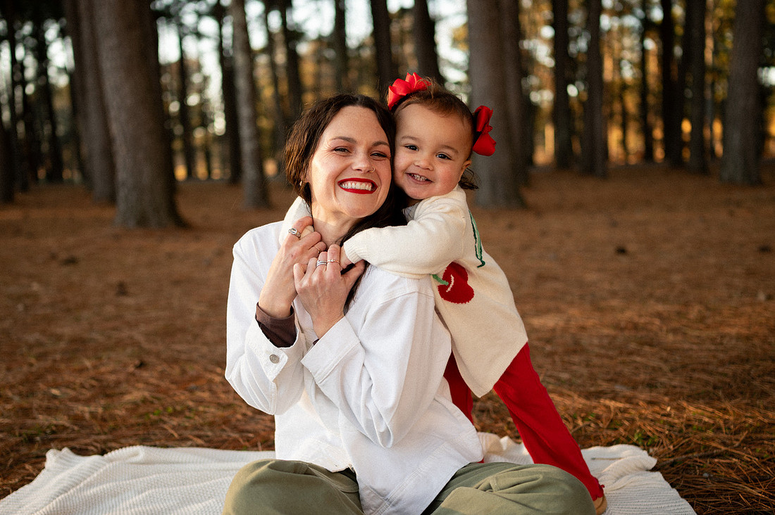 Mother holding her smiling child in a pine grove