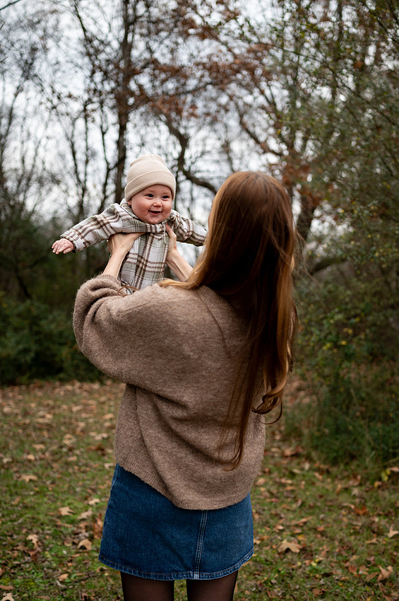 Mother lifting her smiling baby outdoors