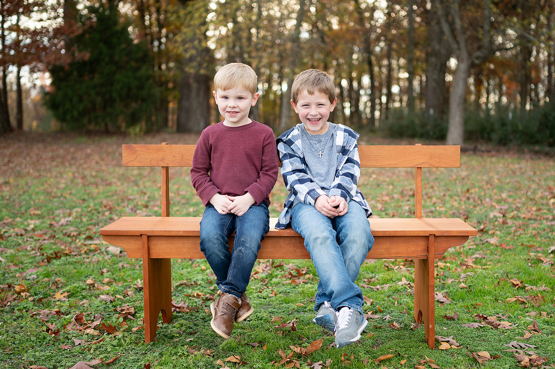 Two young brothers laughing together on a wooden bench